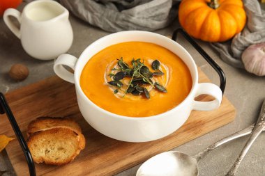 Gri grunge arka planda tohumlu ve otlu lezzetli balkabağı kremalı çorba, yakın plan.