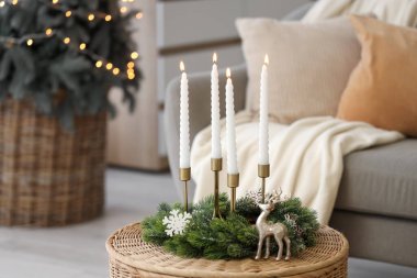 Noel çelengiyle mum yakmak ve oturma odasında sepetin üstünde ren geyiği.