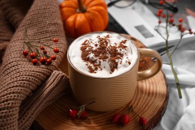 Arka plan olarak beyaz kumaş üzerine bir kupa lezzetli kahve ve süveter, yakın plan