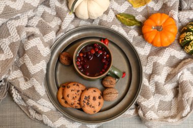 Kareli kompozisyon, arka plan olarak gri kumaş üzerinde lezzetli bir kupa gül kalçası çayı ve kurabiyeler.