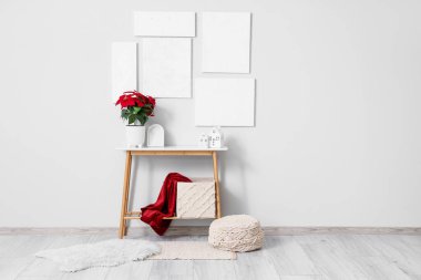 Aydınlatma odasının içinde masa ve tabloların üzerinde Noel bitkisi süsleri var.