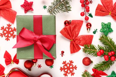 Noel hediyesi kutusunda köknar ağacı dalları ve beyaz arka planda süslemeler var.