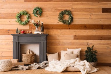 İçinde Noel çelenkleri, şömine rafı ve yastıklar olan oturma odası.