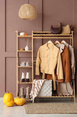 Koridorun içinde giysi, aksesuar ve balkabağı olan ahşap askı.