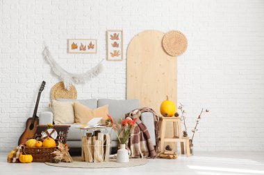 Oturma odasının içinde kanepe, piknik sepeti ve sonbahar dekoru var.