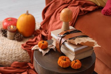 Oturma odasında sonbahar yapraklı, balkabaklı ve mantarlı kitaplar.