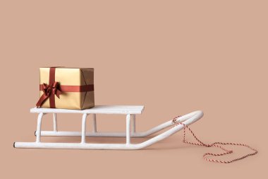 Bej arka planda hediye kutusu olan beyaz kızak.