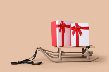 Bej arka planda Noel hediyesi kutularıyla kızak.