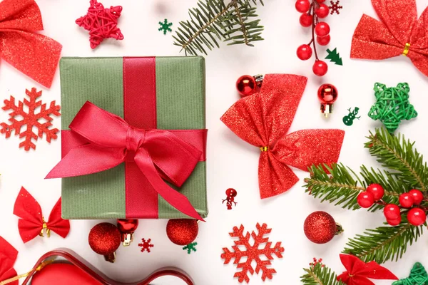 Noel hediyesi kutusunda köknar ağacı dalları ve beyaz arka planda süslemeler var.