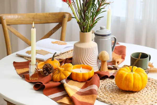 Balkabaklarıyla sonbahar kompozisyonu ve yemek masasında yanan mumlar, yakın plan.