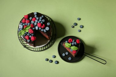 Yeşil arka planda taze böğürtlenli ve nane yapraklı tatlı çikolatalı pasta.