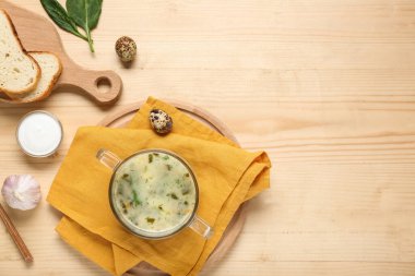 Yumurta, sarımsak, ekşi krema, ıspanak yaprağı ve ahşap zemin üzerinde ekmek dilimleri olan lezzetli yeşil borş çorbası.