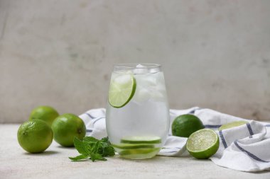 Beyaz zemin üzerinde nane yaprakları olan limonlu su.