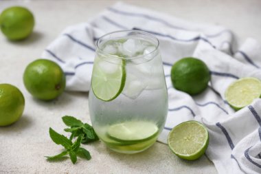 Beyaz zemin üzerinde nane yaprakları olan limonlu su, yakın plan.