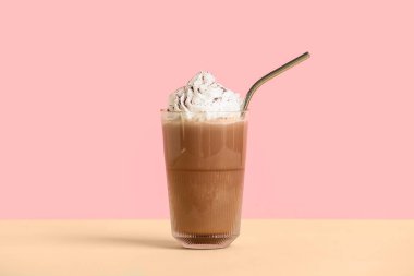 Bir bardak soğuk kakao, krem şanti ve pembe arka planda sarı masa.