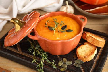 Tahta arka planda çekirdekli, kıtır kıtır ve kekik soslu lezzetli balkabağı kremalı çorba.