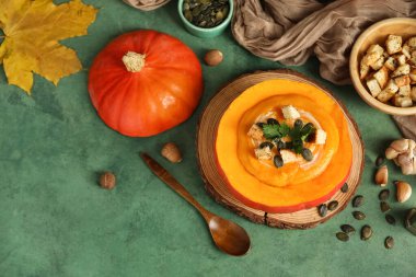 Balkabağında lezzetli krema çorbası ve yeşil grunge arka planda malzemeler.