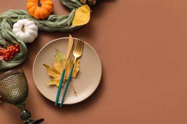 Kahverengi arka planda sonbahar yaprakları ve balkabaklarıyla güzel bir masa.