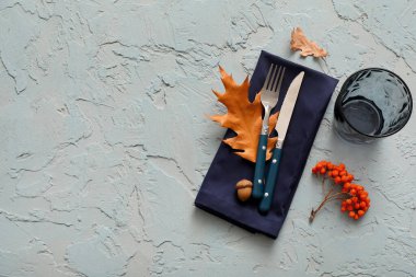 Sonbahar yaprakları, meşe palamudu ve açık mavi arka planda böğürtlenli gümüş çatal bıçak takımı.