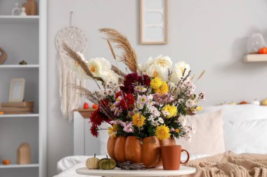 Balkabağı ve sonbahar çiçeği yatak odasındaki masada, yakın plan.