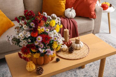 Sonbahar çiçekli balkabağı ve oturma odasındaki masada yanan mumlar, yakın plan.