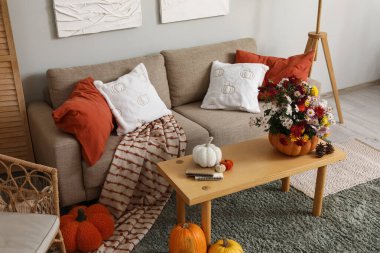 Kanepe, masa ve balkabağı. Oturma odasının içinde güzel sonbahar çiçekleri var.