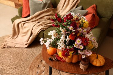 Sonbahar çiçekli balkabağı, mum ve köknar kozalakları oturma odasında, yakın plan.