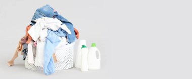 Açık arkaplanda kirli çamaşır sepeti ve deterjan ve metin için yer var.