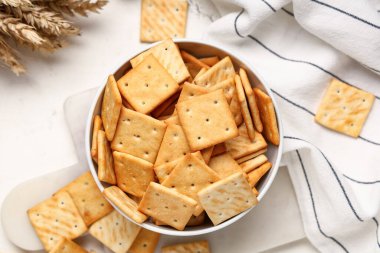 Beyaz arka planda lezzetli krakerler ve buğdaylı kase