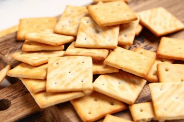 Beyaz arka planda lezzetli krakerler olan ahşap tahta, yakın plan.