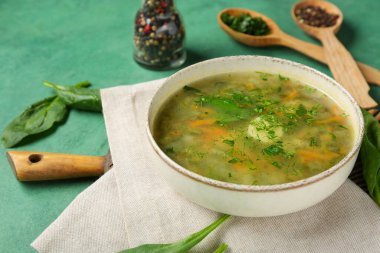 Bir kase lezzetli yeşil borş biber, yeşillik ve yeşil grunge arka planda ıspanak yaprağı.