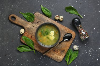 Yumurtalı, ıspanak yapraklı, biberli ve siyah grunge arkaplanlı bir kase lezzetli yeşil borş.