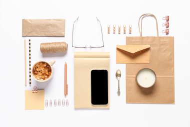 Beyaz arkaplanda cep telefonu, ambalaj ögeleri ve dağıtım kağıt torbasıyla kompozisyon