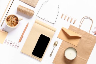 Beyaz arkaplanda cep telefonu, ambalaj ögeleri ve dağıtım kağıt torbasıyla kompozisyon