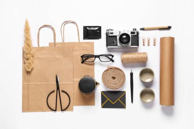 Fotoğraf makinesi, gözlük, ambalaj malzemeleri ve beyaz arkaplanda teslimat kağıdı içeren kompozisyon