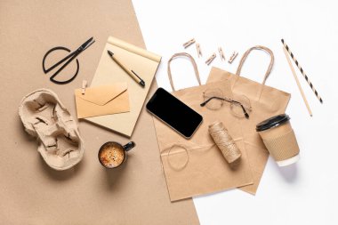 Cep telefonlu kompozisyon, bir fincan kahve, ambalaj malzemeleri ve renk arkaplanına dağıtım kağıdı