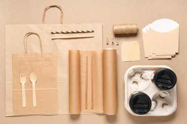 Paket kağıdıyla kompozisyon, kahve fincanları, bej arka planda sicim ve teslimat çantası