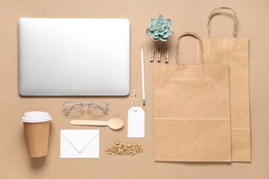 Dizüstü bilgisayarlı kompozisyon, bir fincan kahve, fasulye ve bej arka planda teslimat kağıtları.