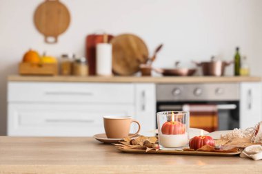 Yanan mumlar, sonbahar dekoru ve mutfaktaki masada bir fincan çay, yakın plan.