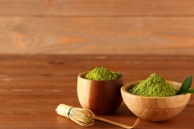 Pudralanmış kiraz çayı, chasen, chashaku ve ahşap arka planda taze yapraklar.