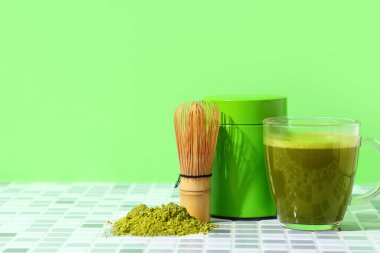 Yeşil duvarda toz, kavanoz ve chasen ile bir fincan taze kibrit çayı.