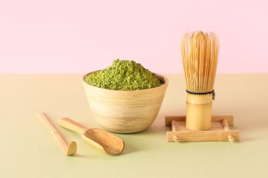 Pudralanmış kibrit çayı, chasen, chashaku ve renkli arka planda kepçeyle kase