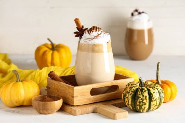 Beyaz masada krem şantili ve tarçınlı bir bardak sıcak kabaklı latte.