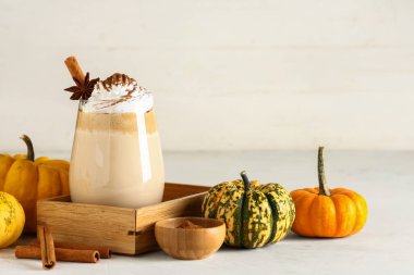 Beyaz masada krem şantili ve tarçınlı bir bardak sıcak kabaklı latte.