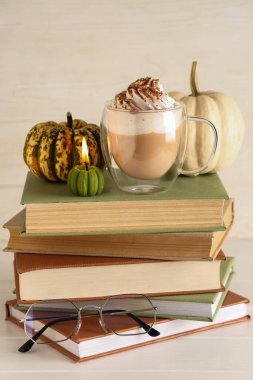 Krem şantili, cam bardak sıcak balkabaklı latte ve beyaz ahşap arka planda yanan mum.