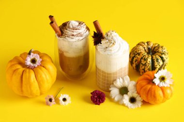 Krem şantili sıcak balkabaklı latte ve sarı arka planda güzel çiçekler.