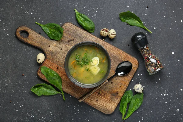 Yumurtalı, ıspanak yapraklı, biberli ve siyah grunge arkaplanlı bir kase lezzetli yeşil borş.