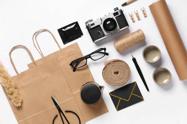 Fotoğraf makinesi, gözlük, ambalaj malzemeleri ve beyaz arkaplanda teslimat kağıdı içeren kompozisyon