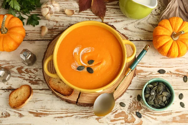 Tohumlu, kızarmış ekmek, sarımsak ve kaşık ile ahşap zemin üzerinde lezzetli balkabağı kremalı çorba