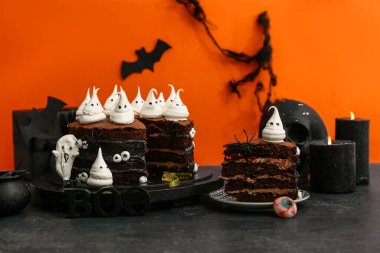 Tatlı cadılar bayramı pastası, hayaletler, gözler ve kelime BOO siyah masada turuncu arka planda